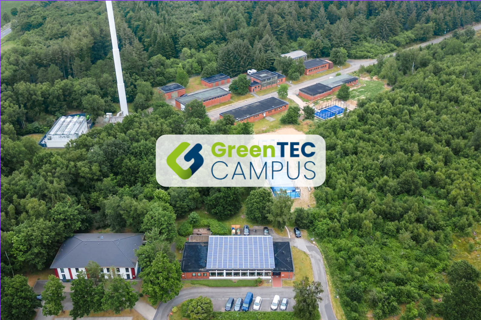 Luftaufnahme des GreenTEC Campus in Enge-Sande, eingebettet in eine grüne Waldlandschaft, mit sichtbaren Solaranlagen und modernen Gebäuden – ein Reallabor für Nachhaltigkeit und Zukunftstechnologien.