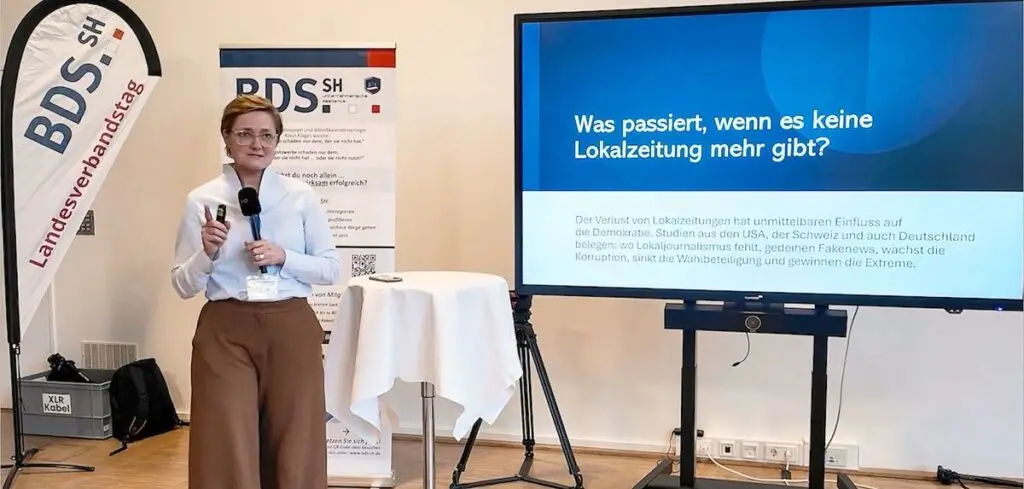 Simone Lange hält einen Vortrag bei einer Veranstaltung des BDS Schleswig-Holstein. Auf dem Bildschirm steht die Frage: „Was passiert, wenn es keine Lokalzeitung mehr gibt?
